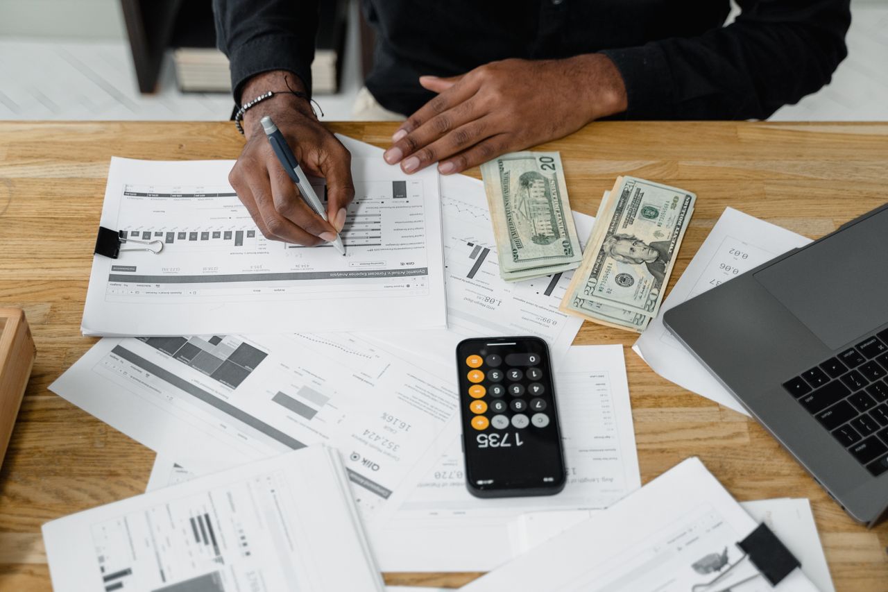 Crafting Captivating Headlines: Your awesome post title goes here Man working on financial reports with calculator, money, and laptop on a desk.